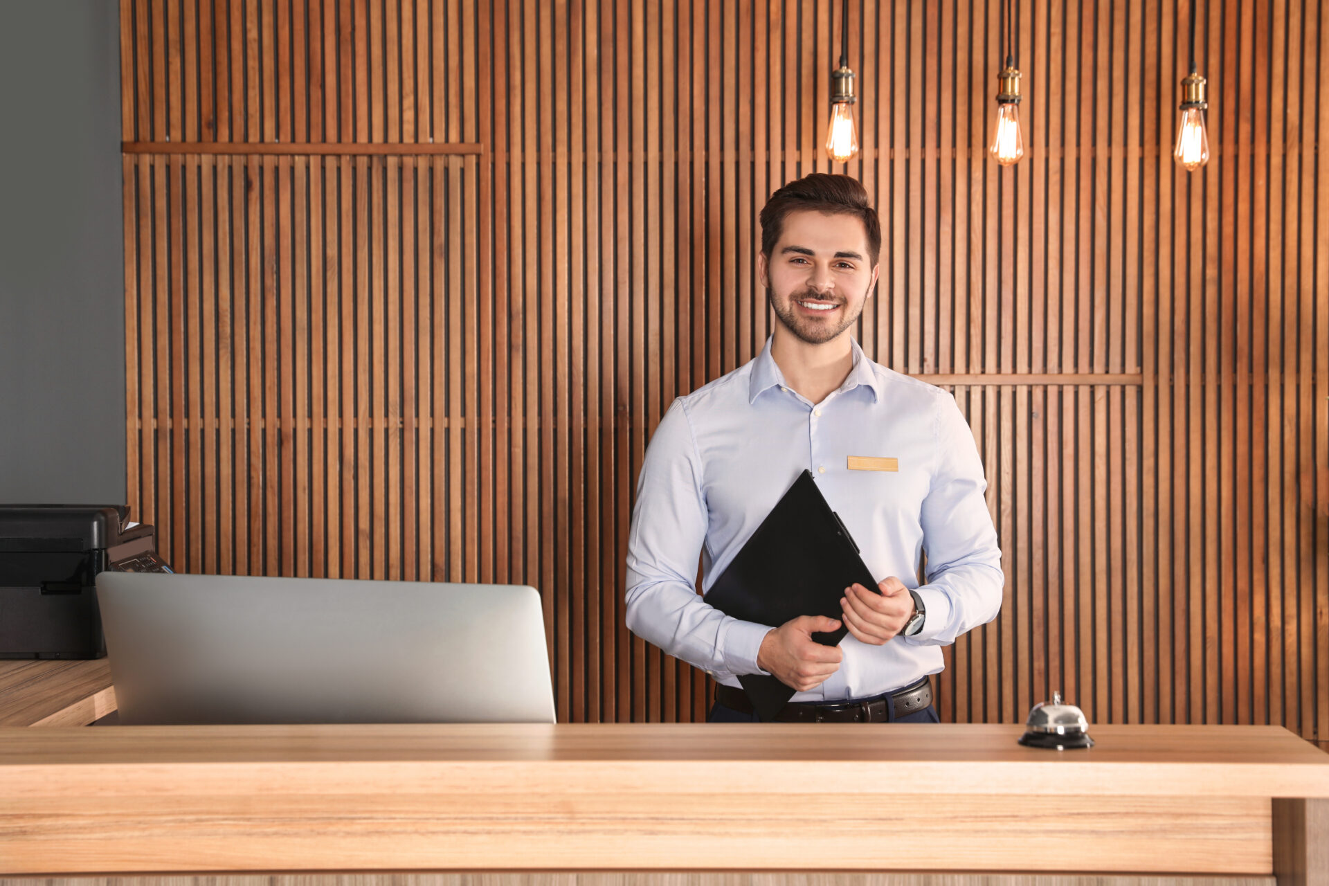 Portrait Of Receptionist With Clipboard At Desk In Lobby